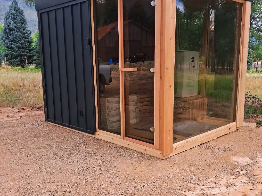 Black Cube sauna with cedar framing and a glass corner, photographed on install day