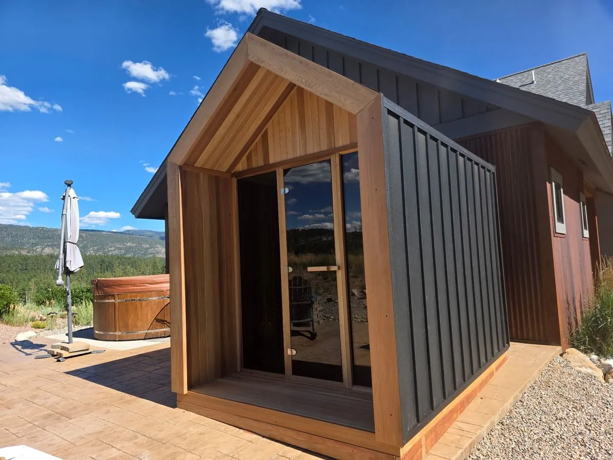 Cedar gable sauna installed beside a hot tub on a stamped concrete patio